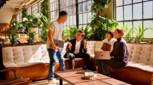 Des collègues discutent et travaillent ensemble dans un espace de coworking lumineux et verdoyant.