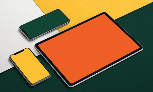 Une tablette et deux smartphones avec des écrans de couleurs unies orange, jaune et vert, posés sur un fond géométrique multicolore.