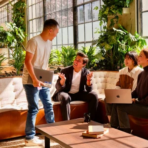 Des collègues discutent et travaillent ensemble dans un espace de coworking lumineux et verdoyant.